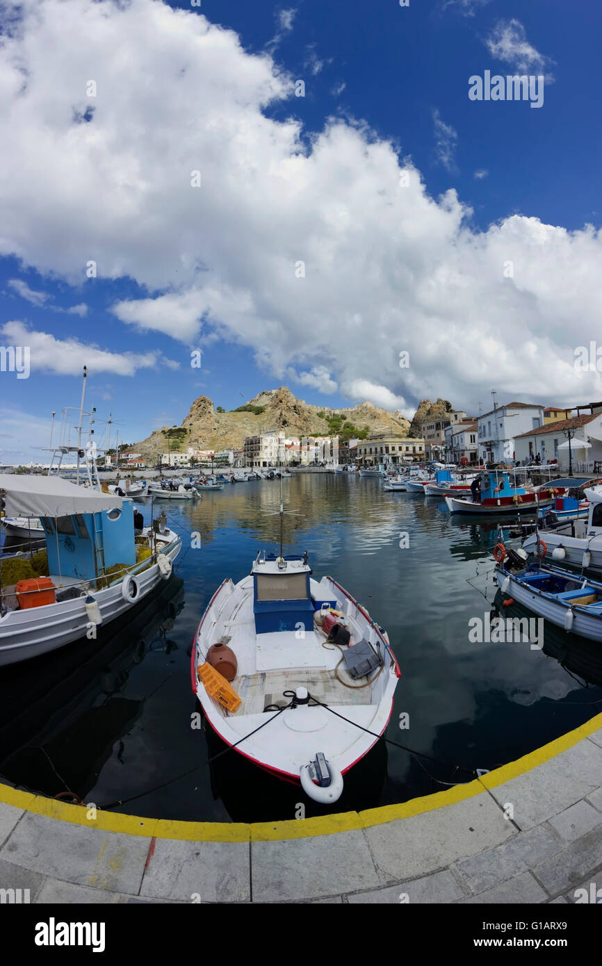 Lemnos quay lit by dramatic cloudy weather, Myrina's Byzantine castle afar, boats & reflections in the foreground. Lemnos Greece Stock Photo