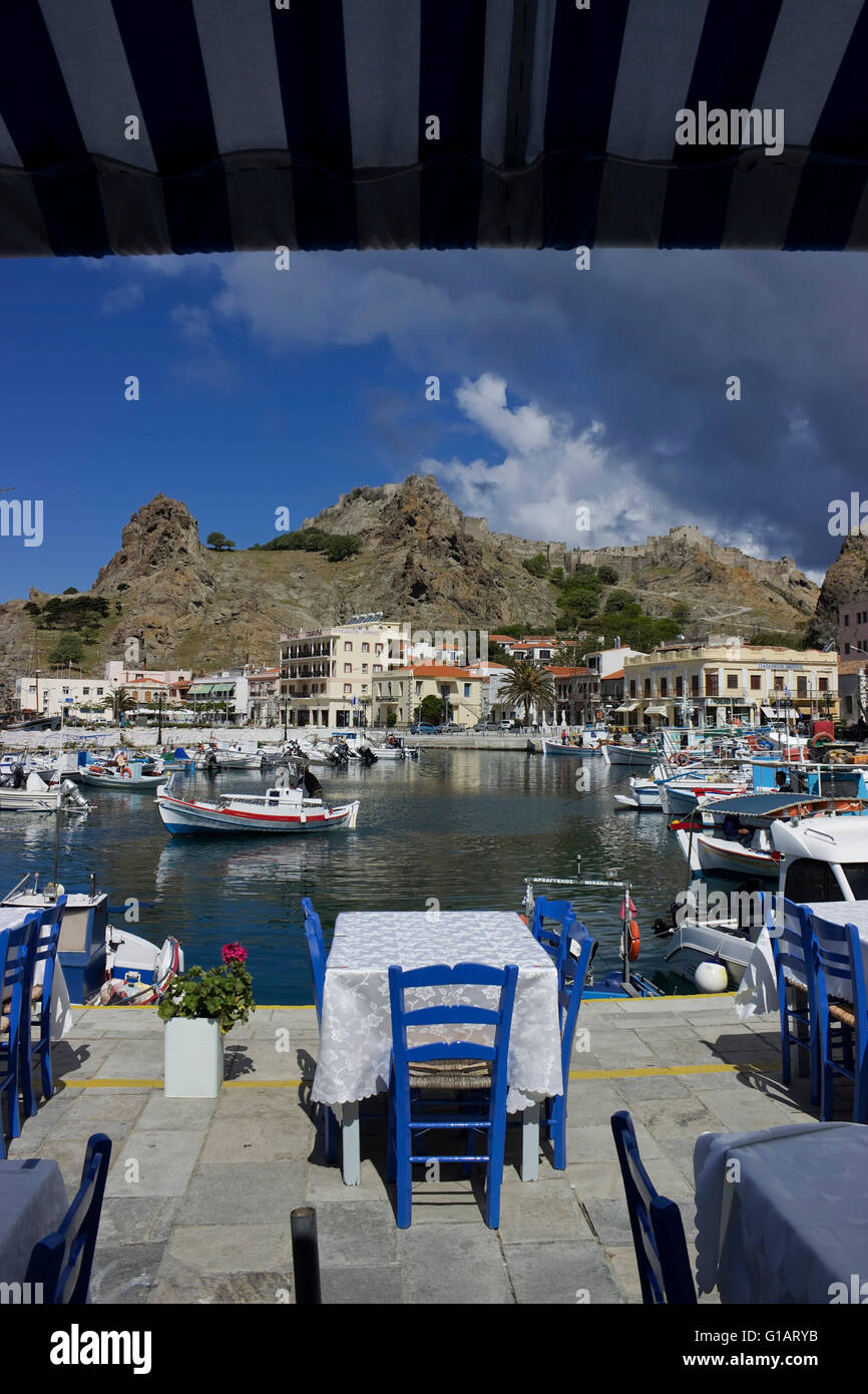 Fish restaurant tables with seats, overlooking the Byzantine fortress part of Myrina's scenic scenery. Lemnos or Limnos, Greece Stock Photo