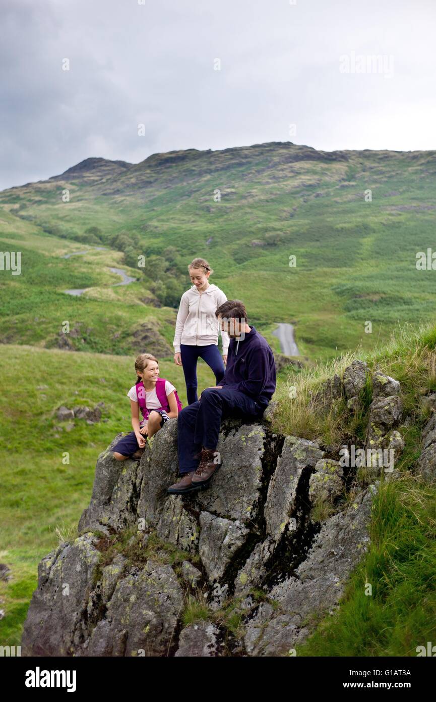 Family of walkers resting on rocks in Wrynose bottom.  Cumbria English Lake District Stock Photo