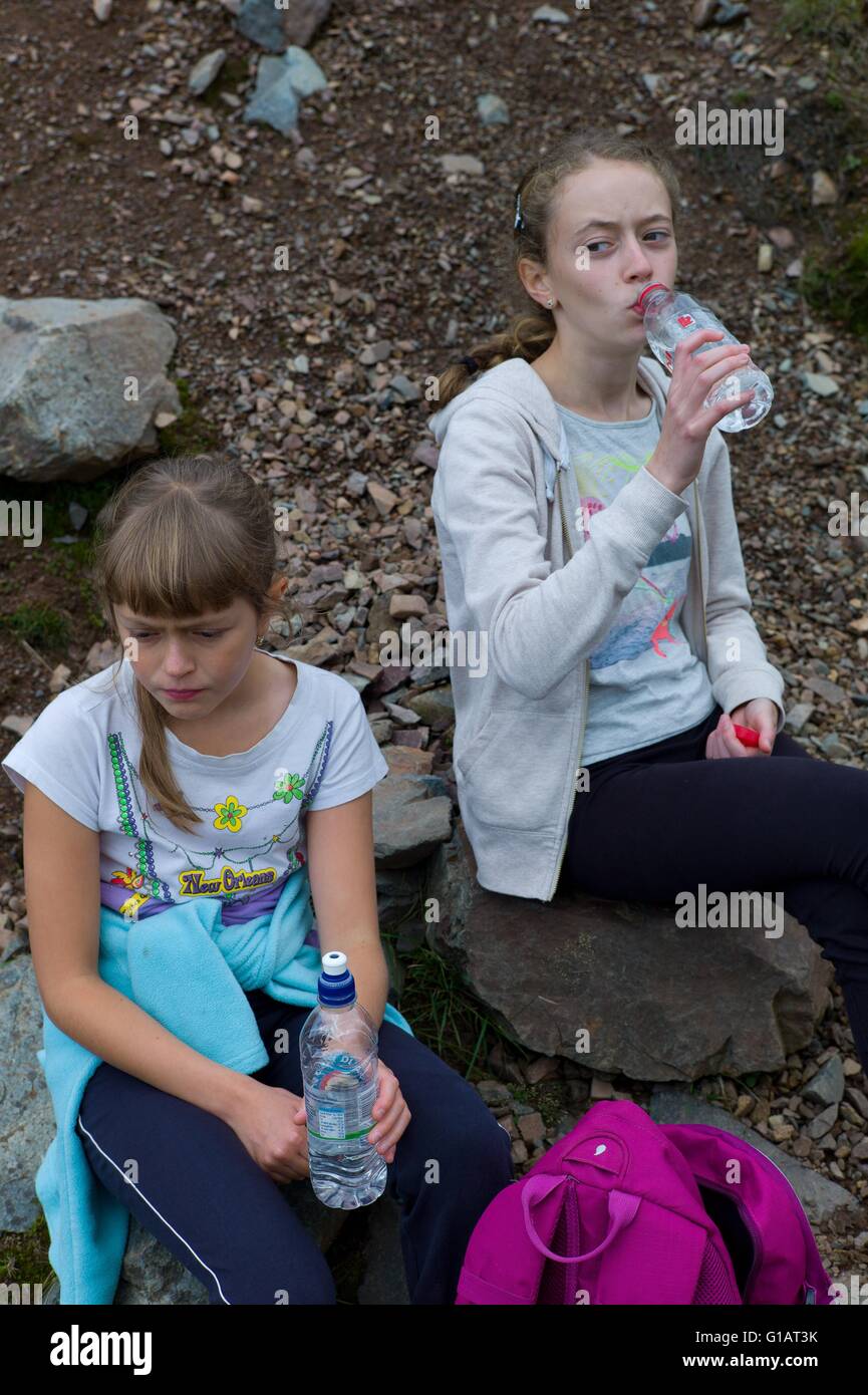 Tired children drinking water on a walk in the Lake District Cumbria UK Stock Photo