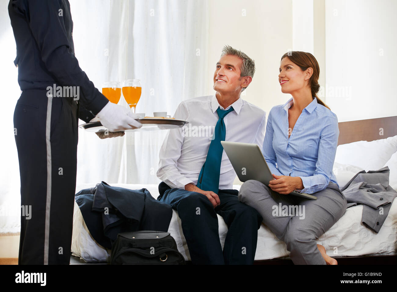 Room service bringing drinks to business couple in a hotel room Stock