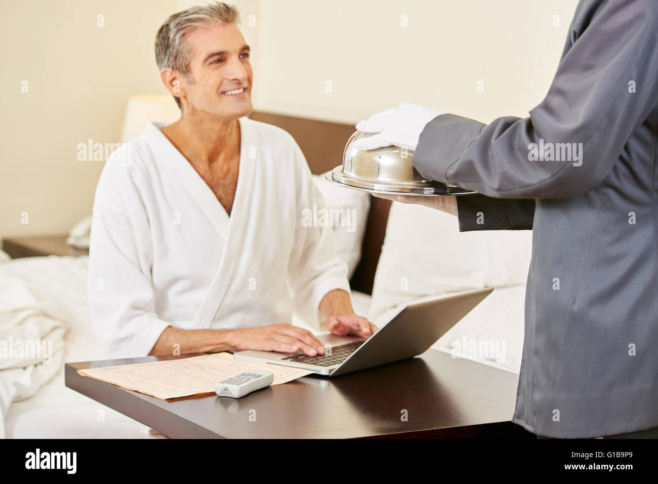 Room service bringing food to a guest with laptop computer in a hotel