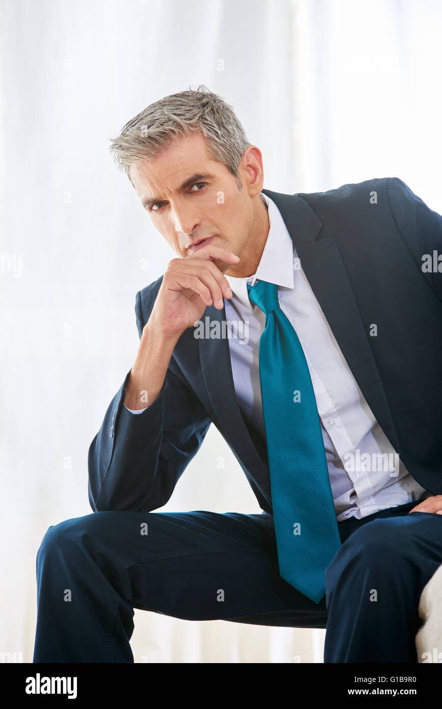 Pensive business man sitting thoughful in a hotel room Stock Photo
