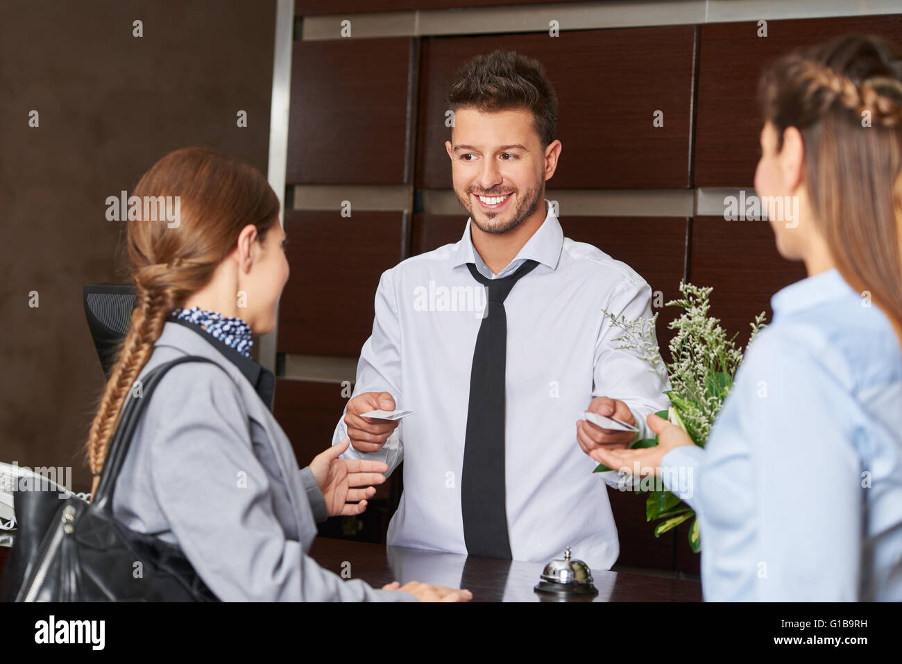 Hotel receptionist giving out key cards to guests Stock Photo