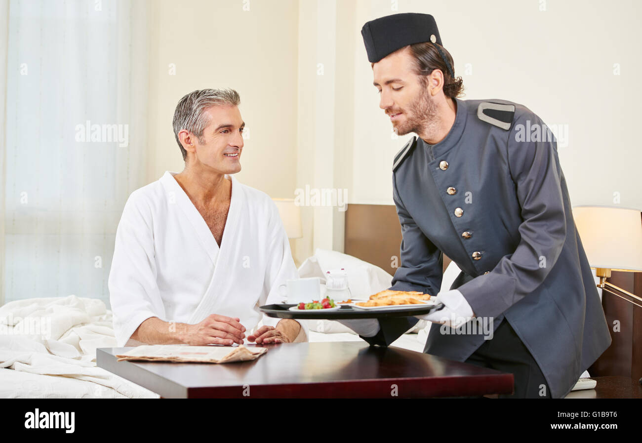 Page bringing breakfast to guest in a hotel room Stock Photo
