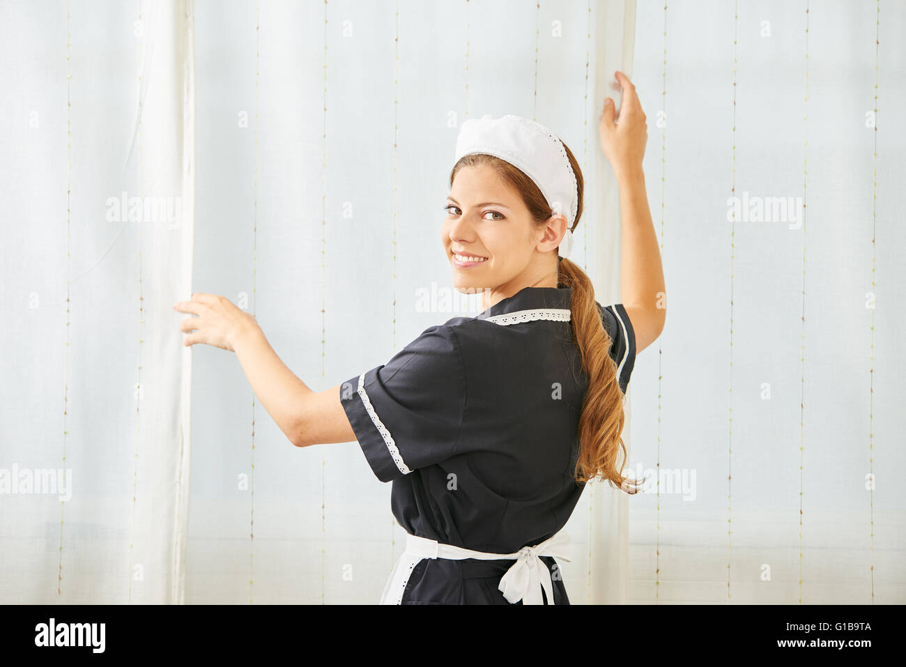 Smiling maid in hotel room cleaning during housekeeping Stock Photo