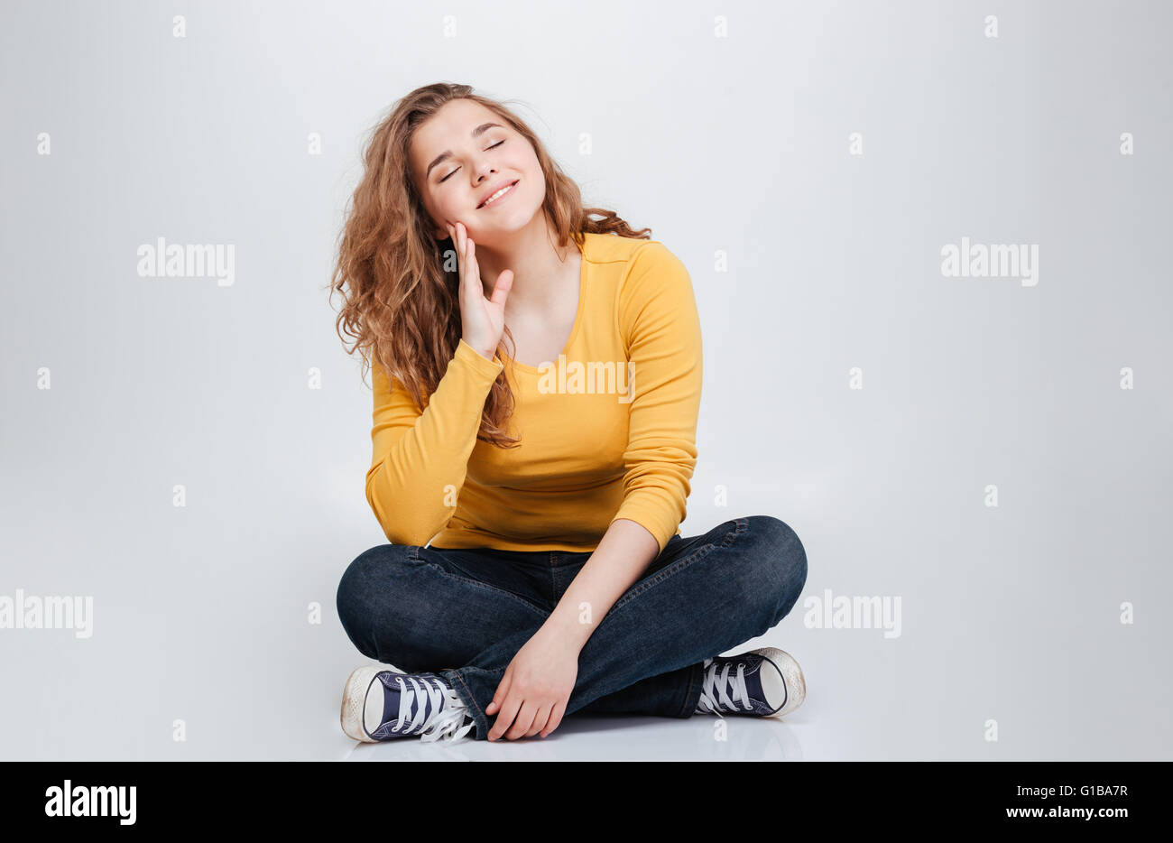 Happy relaxed woman sitting on the floor with closed eyes isolated on a ...