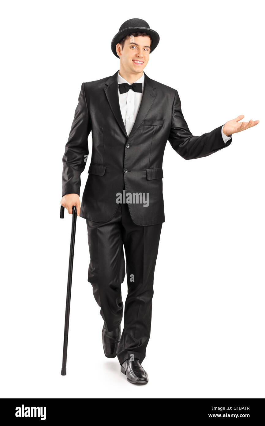 Full length portrait of a young gentleman in a fancy black suit walking with cane isolated on