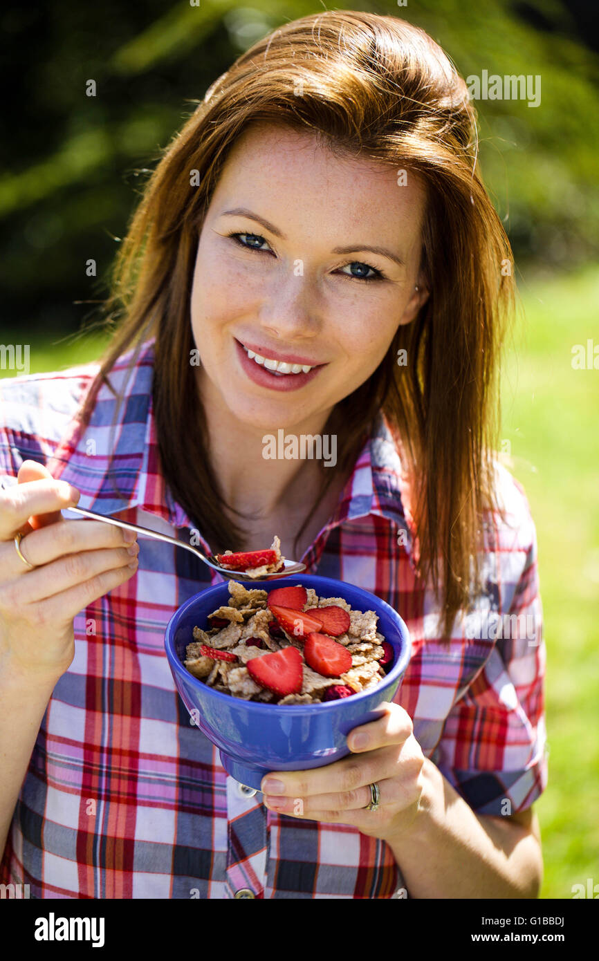 Portrait of a Woman Outside Eating Healthy Breakfast Cereals with Fresh Strawberries Fruit Stock Photo