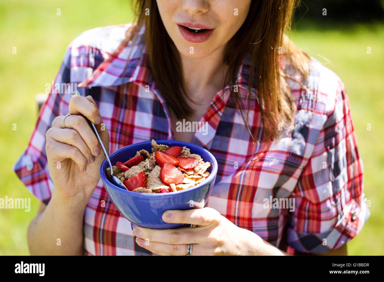 Portrait of a Woman Outside Eating Healthy Breakfast Cereals with Fresh Strawberries Fruit Stock Photo
