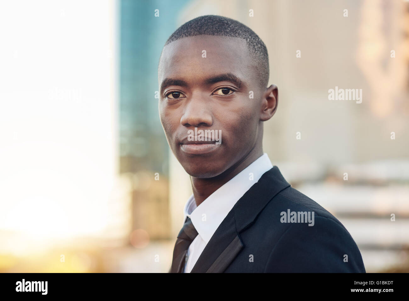 Closeup head and shoulders portrait of a confident entrepreneur of African descent wearing a suit and tie standing outdoors look Stock Photo