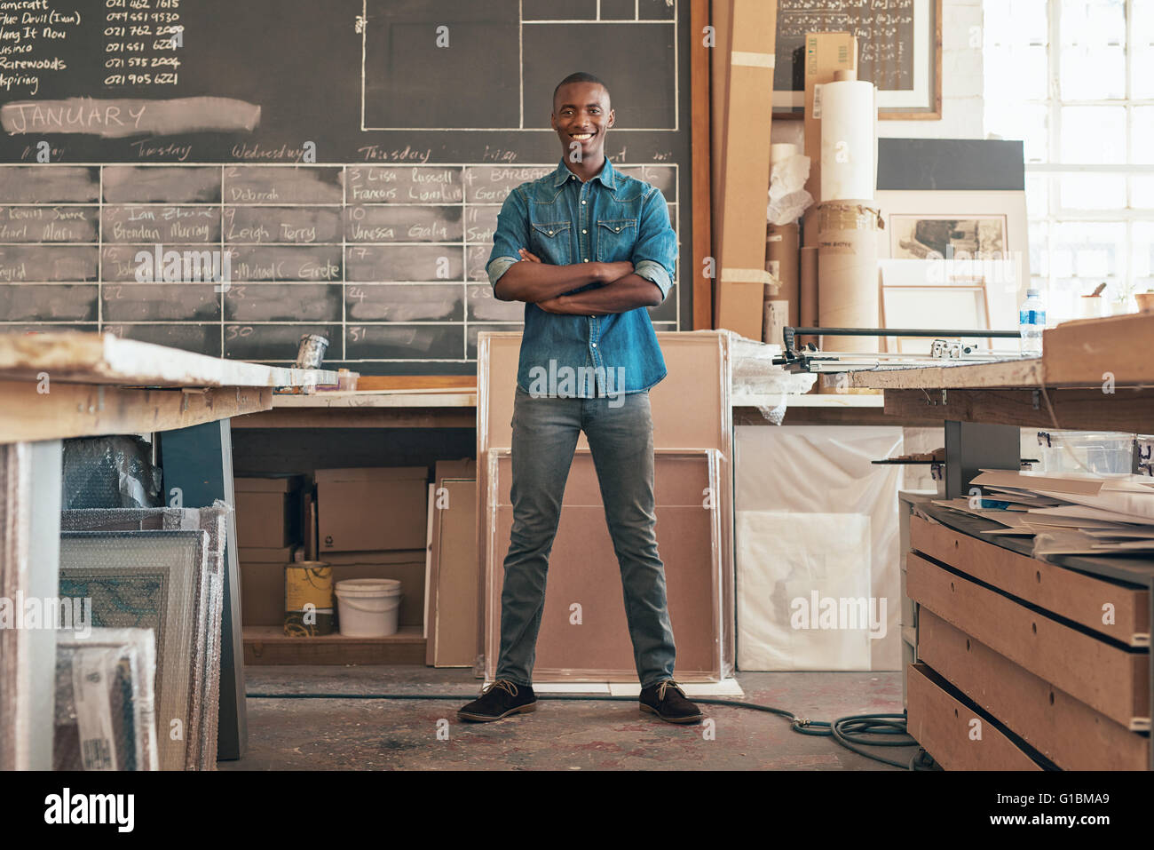 Full length portrait of a handsome young business owner of African descent, standing with his arms crossed and smiling confident Stock Photo