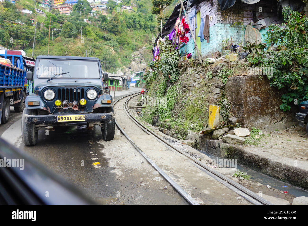 A Mahindra Jeep on National Highway 55 standing besides the Darjeeling Himalayan Railway Toy Train track. Stock Photo