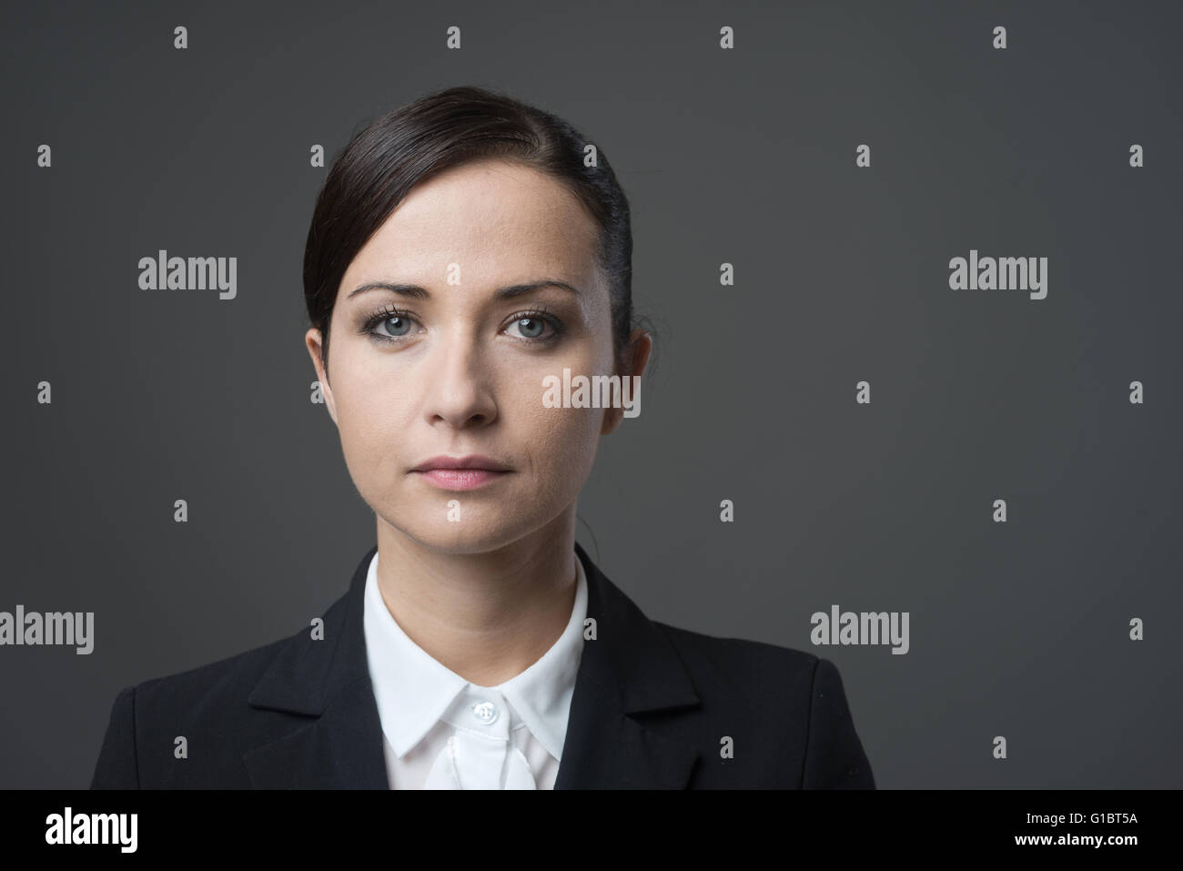 Serious businesswoman looking at camera on gray background, confident attitude. Stock Photo