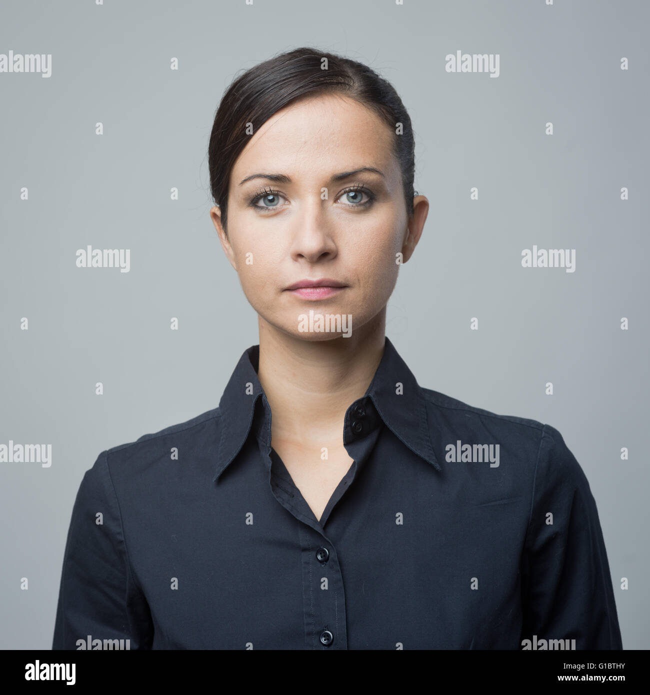 Serious confident woman in blue shirt staring at camera. Stock Photo