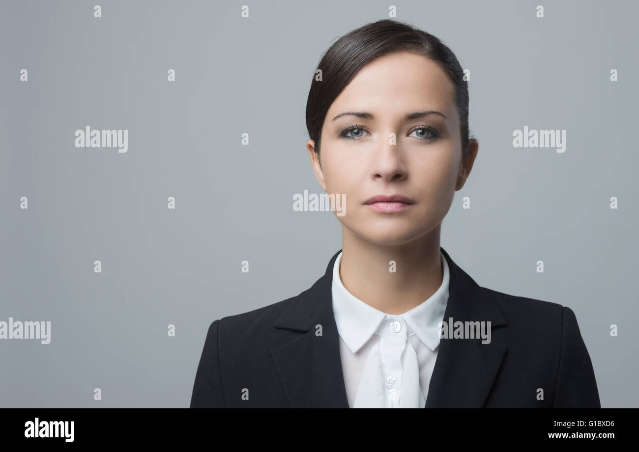 Serious confident businesswoman staring at camera and posing on gray background. Stock Photo