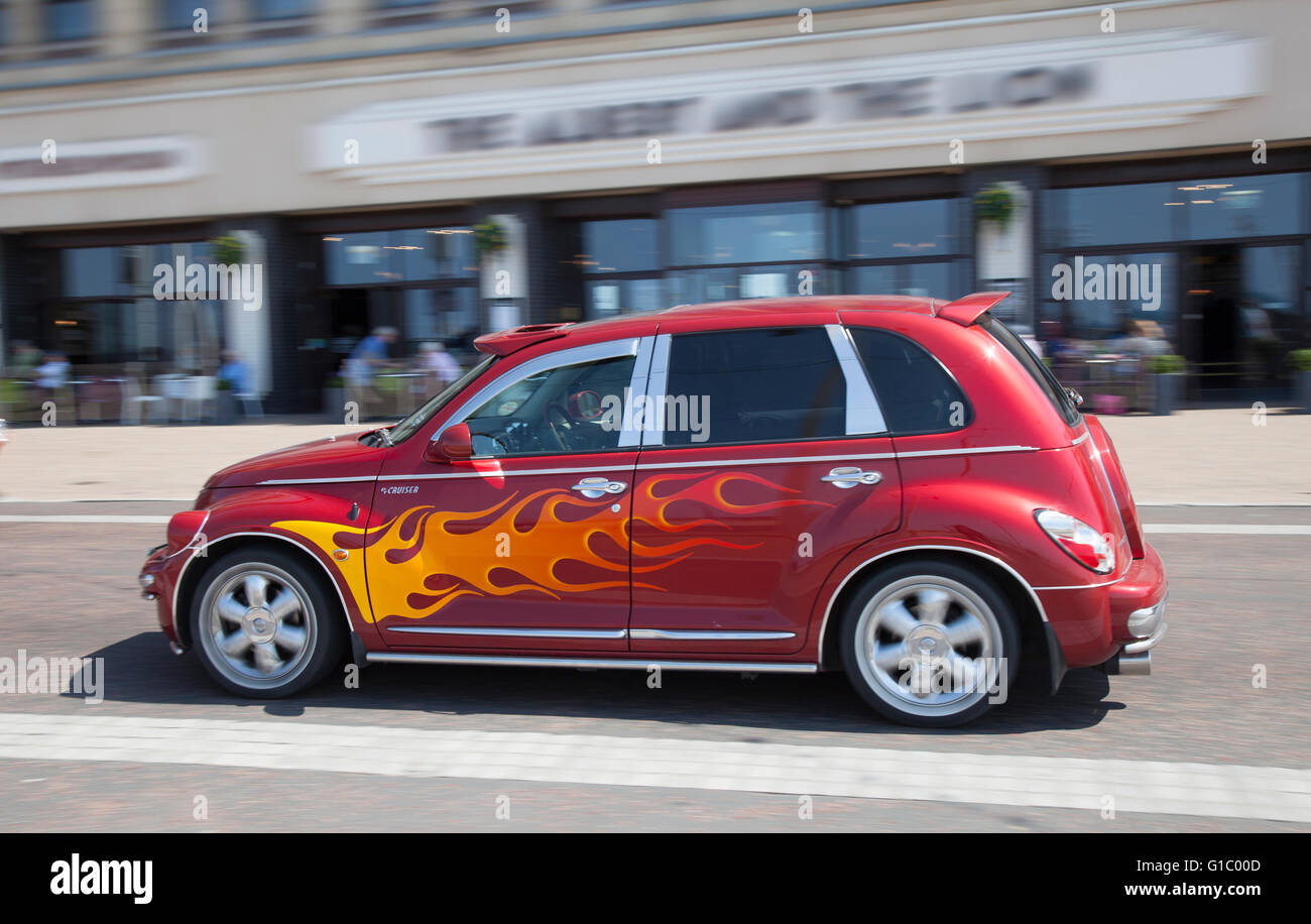 Painted flames on Cars. Custom car, Street rods and Hot rods with Flaming wheels, & blacked out windows on a moving Customised red Chrysler Cruiser, Blackpool, Lancashire, UK Stock Photo