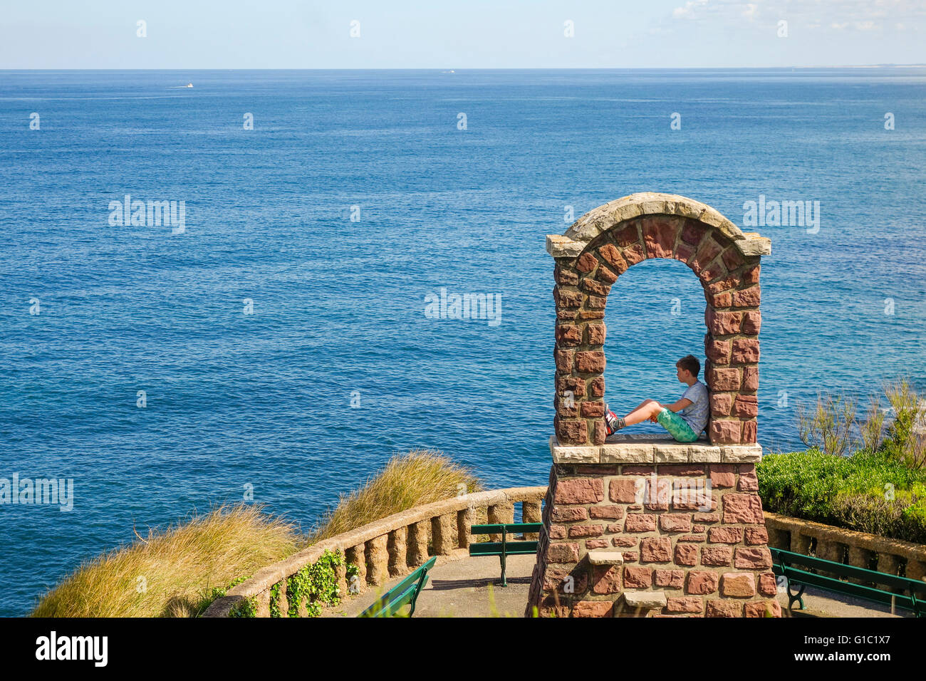 Boy sits in ancient bell tower, Biarritz, Plateau Atalaye, Aquitaine, Basque country, France. Stock Photo