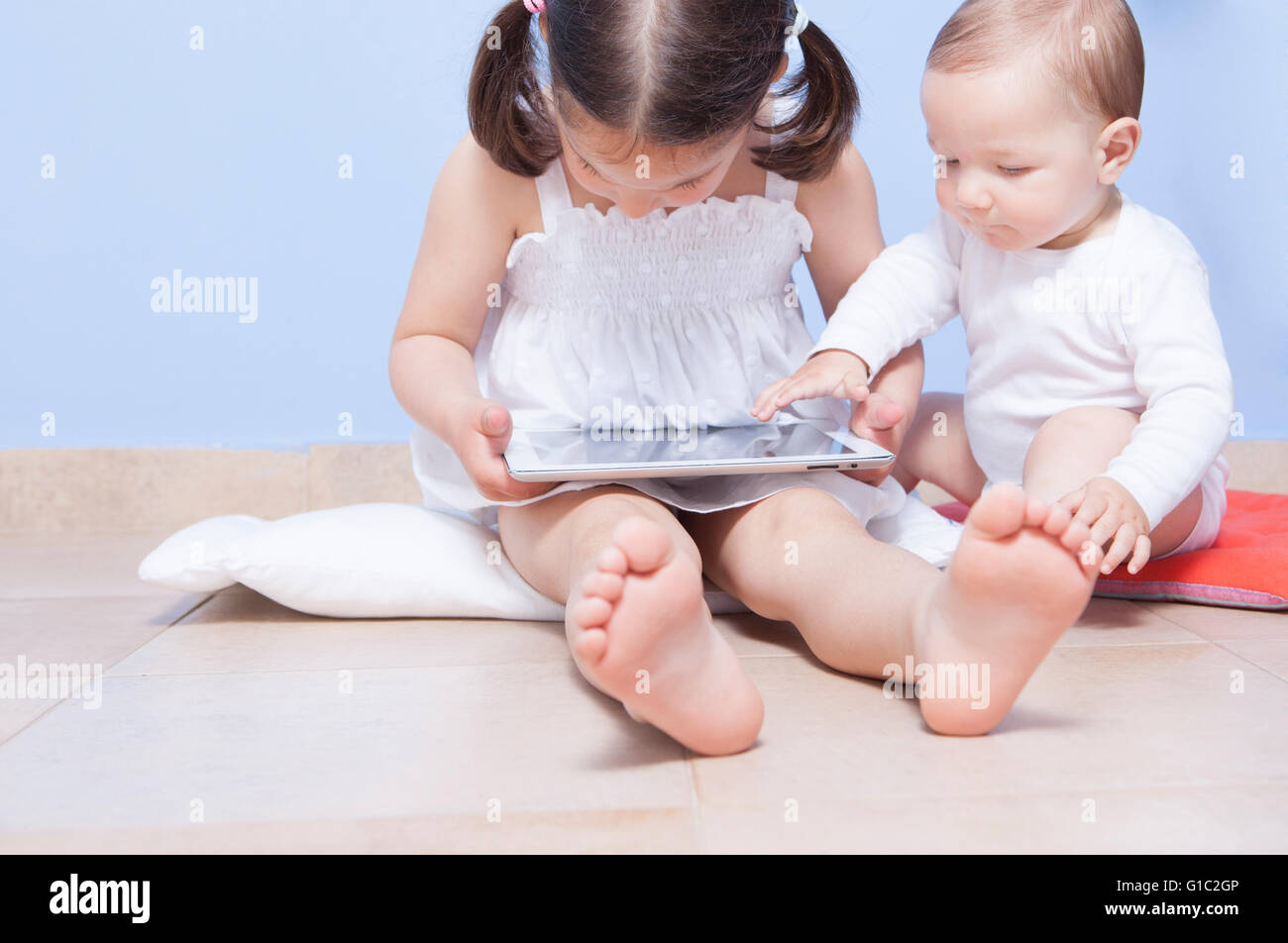 Baby boy discovering with her sister a tablet pc Stock Photo