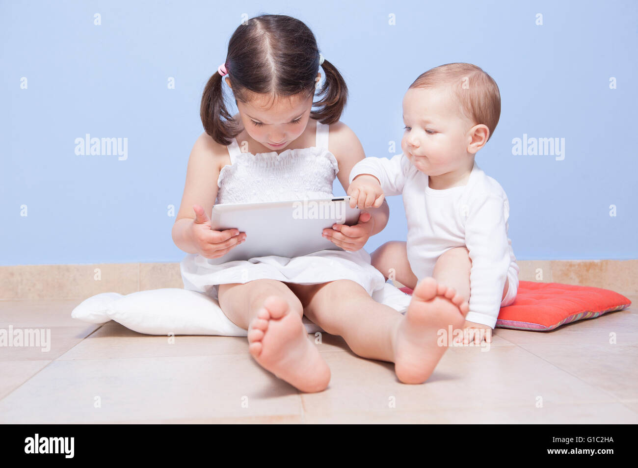 Baby boy discovering with her sister a tablet pc Stock Photo