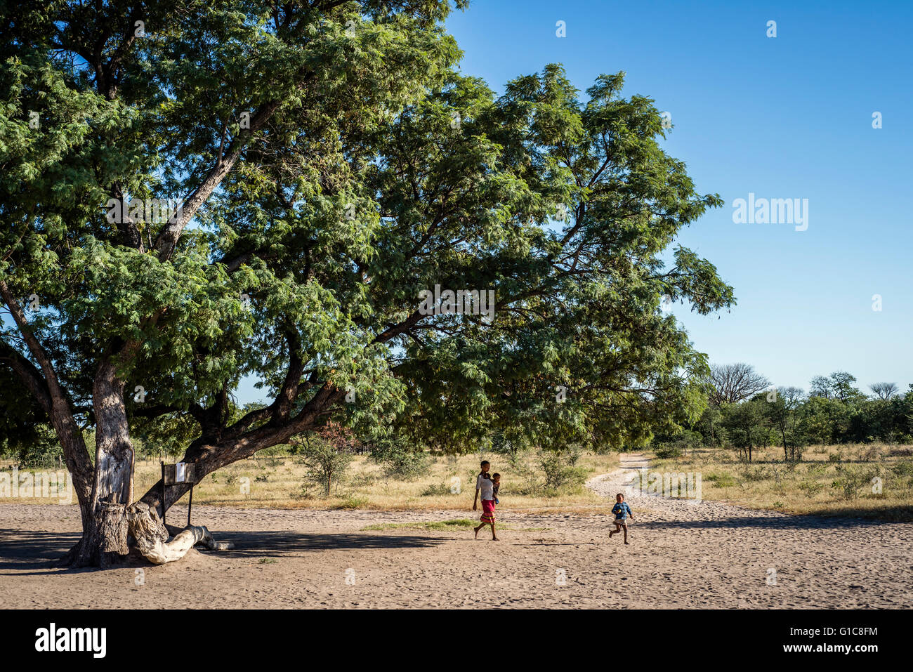 San woman with two children walking to the village. Grashoek, Living Museum of the Ju’Hoansi-San, Namibia Stock Photo