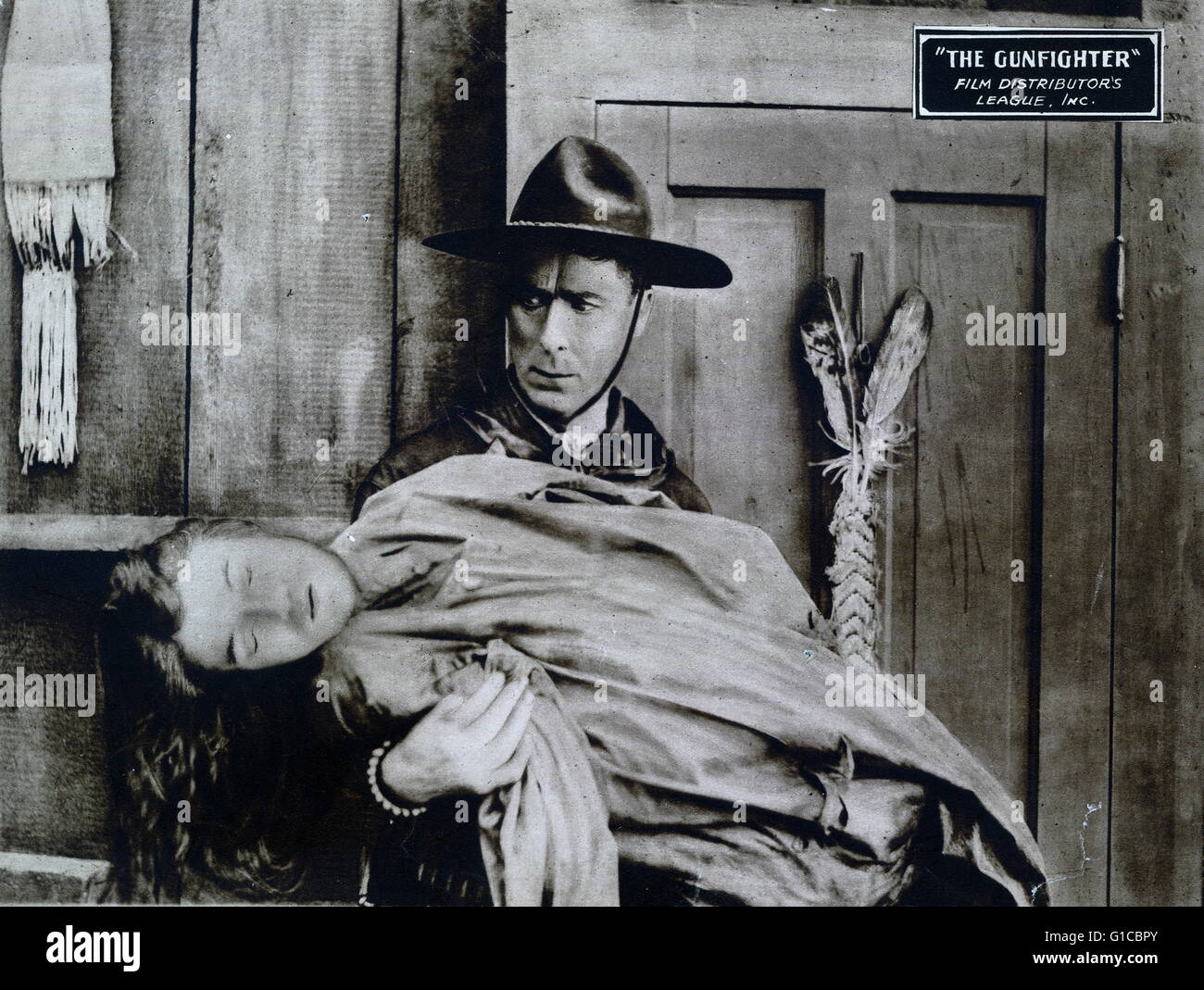 Motion picture lobby card for 'The gunfighter' shows a man standing in doorway holding unconscious woman in his arms. Dated 1923 Stock Photo