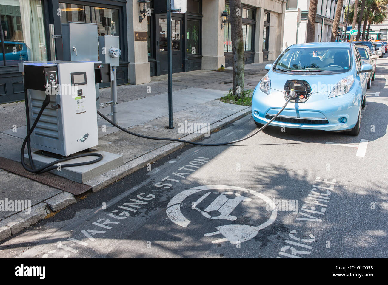 A Nissan Leaf electric car gets a charge from a public SigNet charging station on Bull Street in Savannah, Georgia. Stock Photo