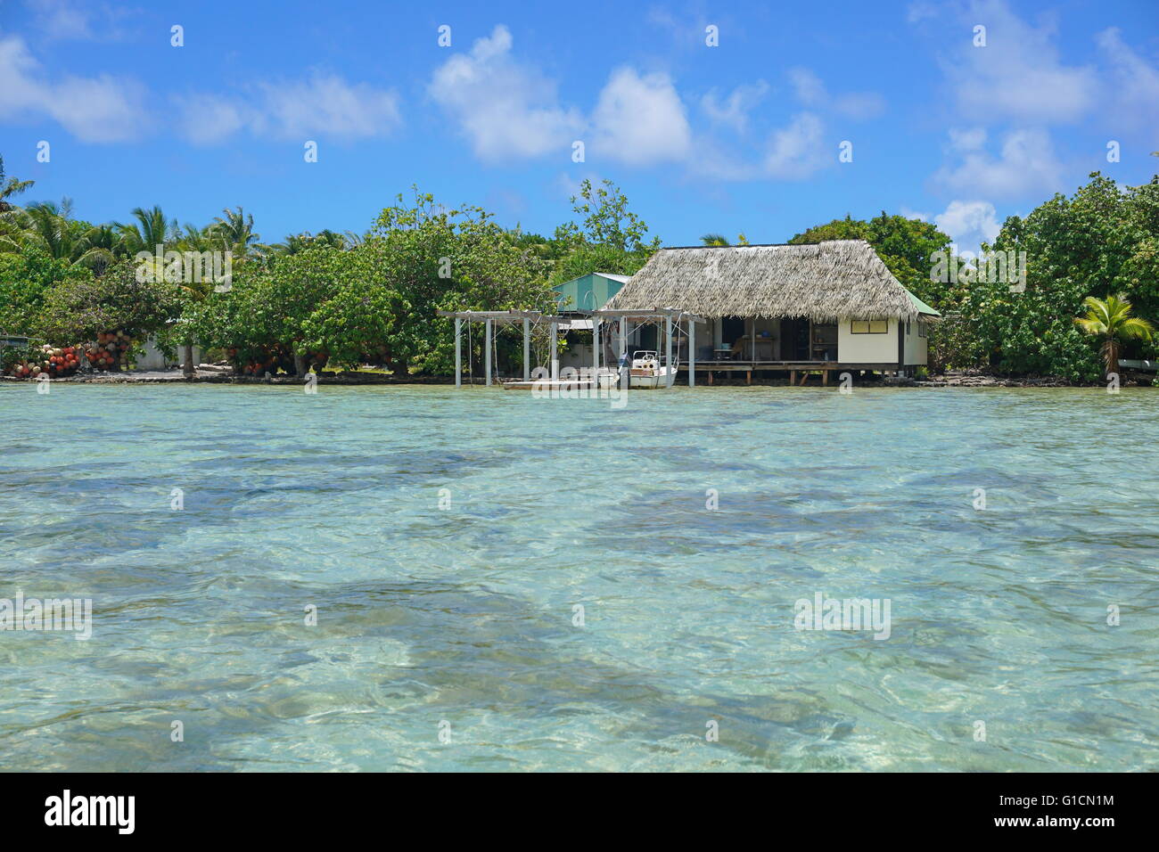 Shallow water of the lagoon with typical home on the shore of an islet, Huahine island, Pacific ocean, French Polynesia Stock Photo