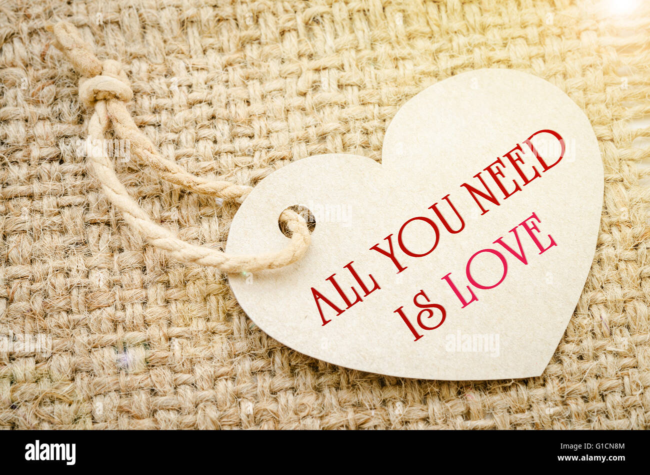 All you need is love on brown paper price tags Heart shapes with brown rope on sack background. Recycled paper. Stock Photo