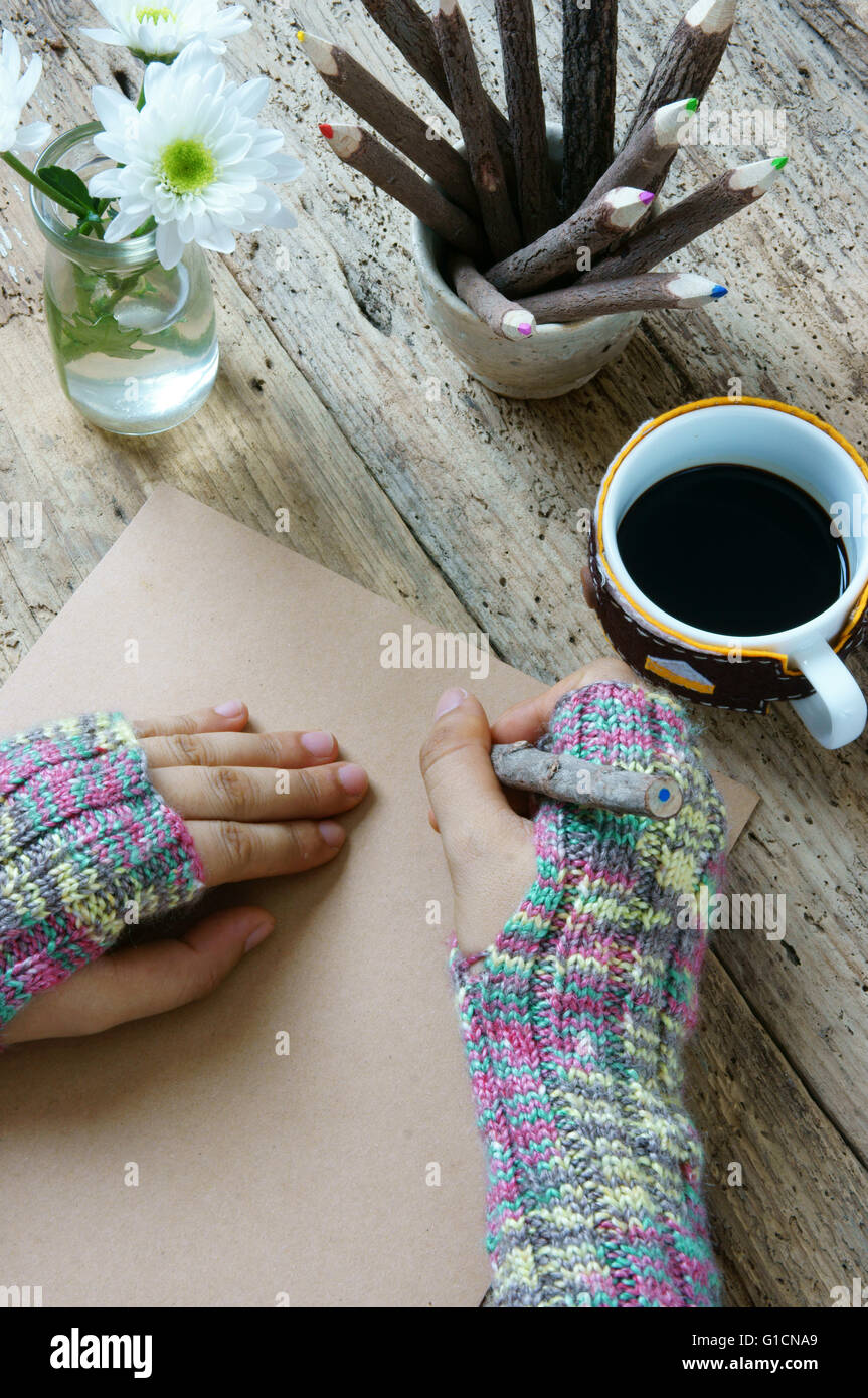 Women hand wear wool gloves in wintertime, writting letter for lover from distant, lonely  in cold day of christmas season with hot coffee cup Stock Photo