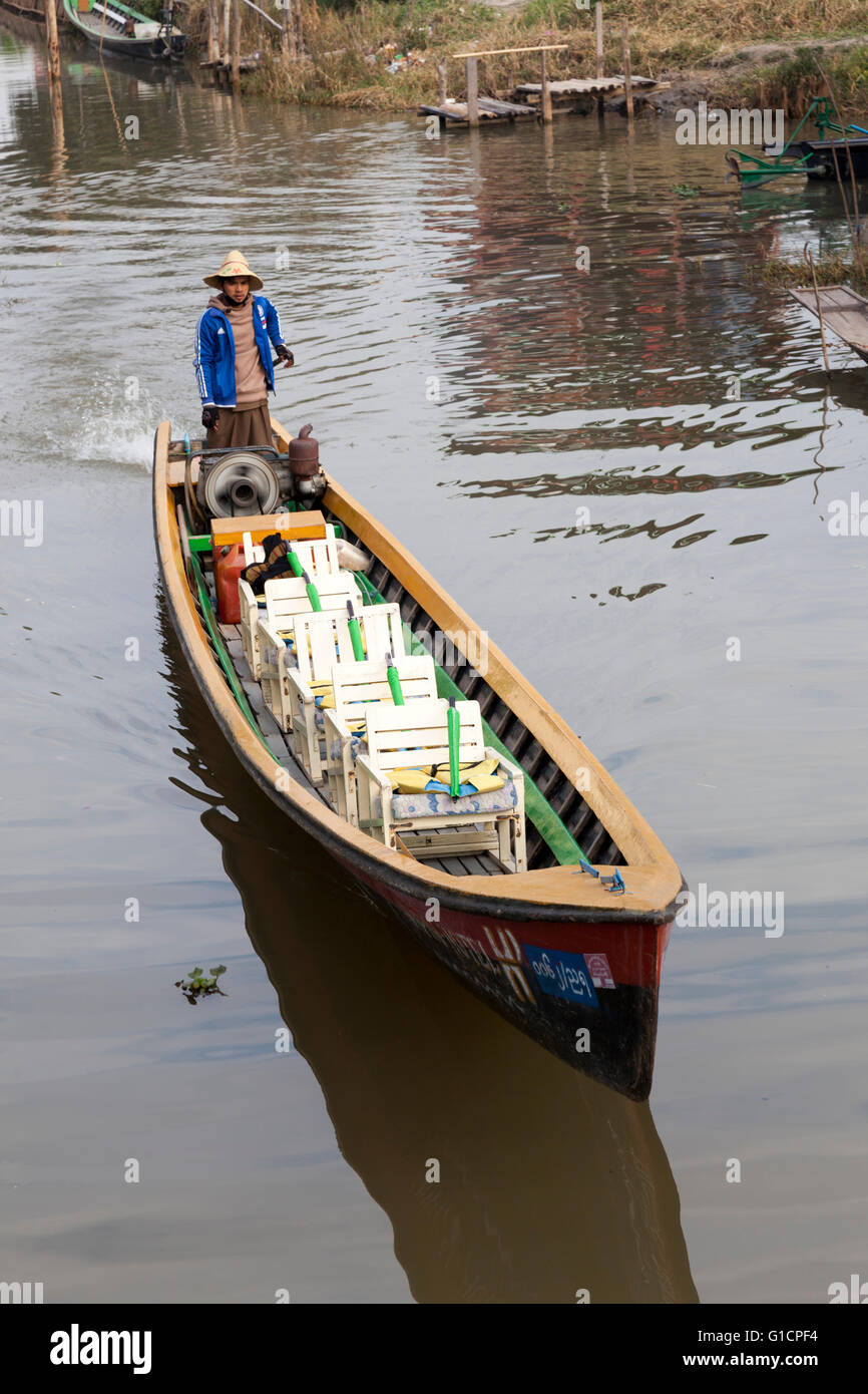 A tourist boat going off again empty on the Inle Lake (Myanmar). These boats for trips all have seats put up in single file. Stock Photo