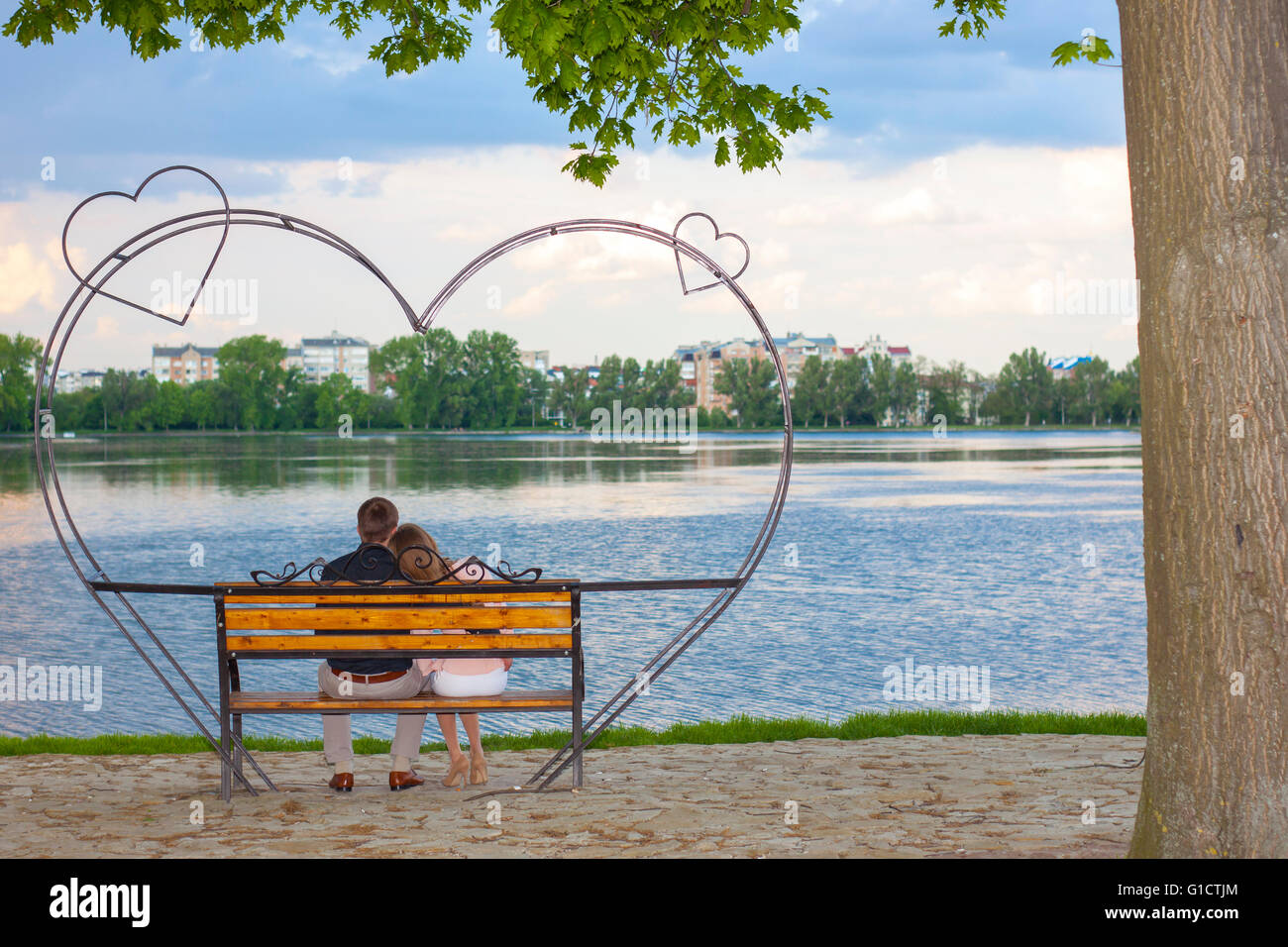 Couple sitting on a bench in front of  big lake Stock Photo