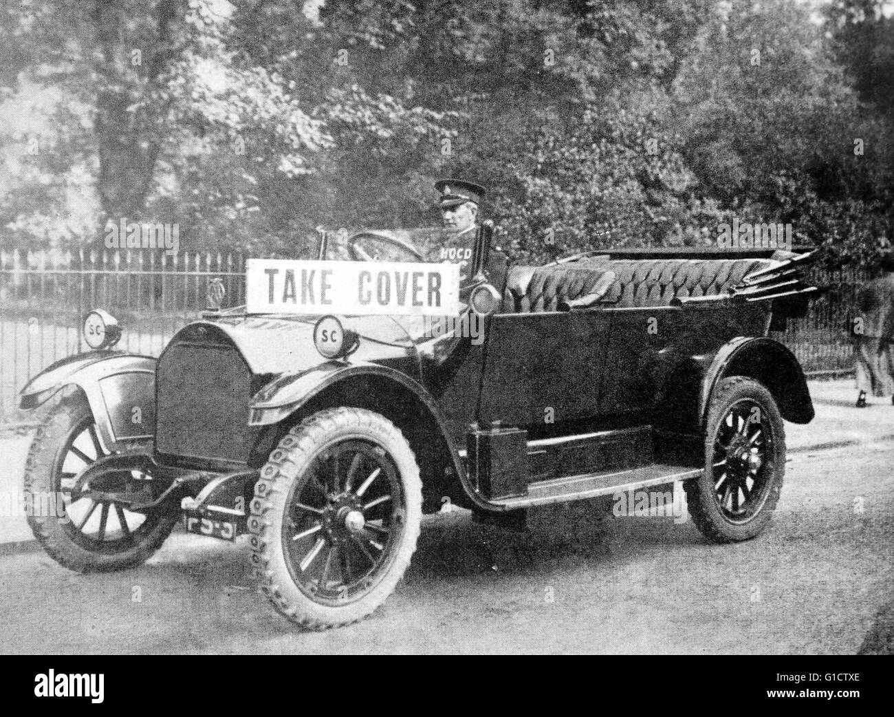 First World War air raid warden driving a car with a warning card saying 'take cover' during a German air raid in London 1916 Stock Photo