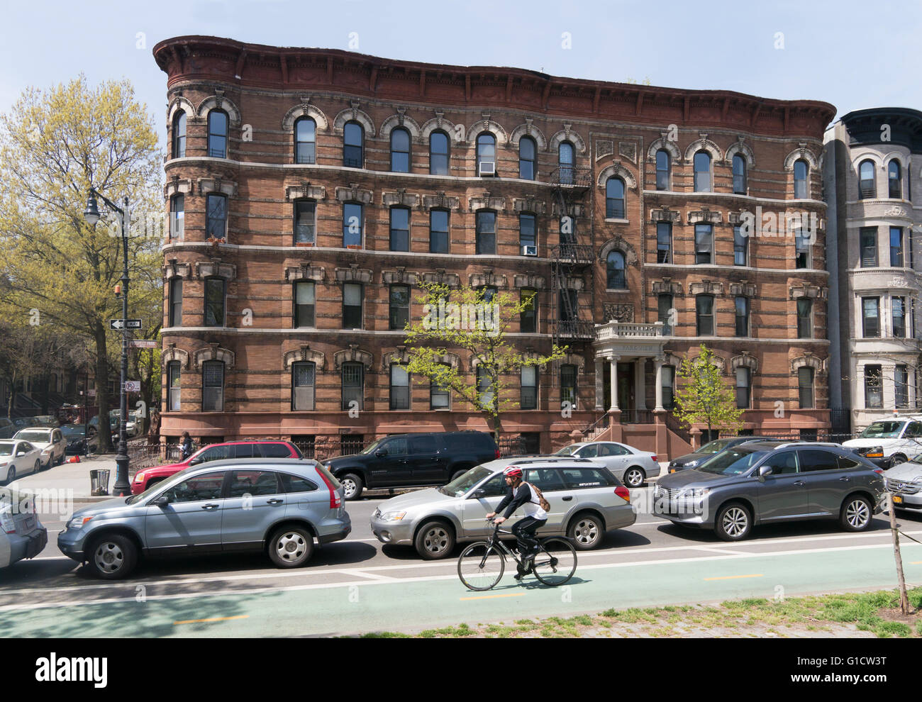 Man cycling along Prospect Park West cycle path with apartment building in background, Brooklyn, New York, USA Stock Photo