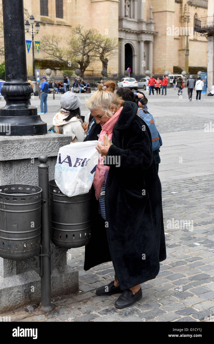 Woman scavenging for food in litter bin in Segovia Spain Stock Photo