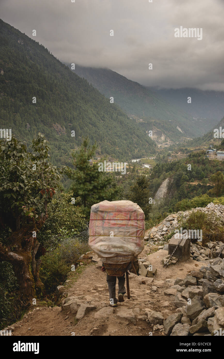 Sherpa carrying some serious weight on the way to Namche Bazaar in Nepal Stock Photo
