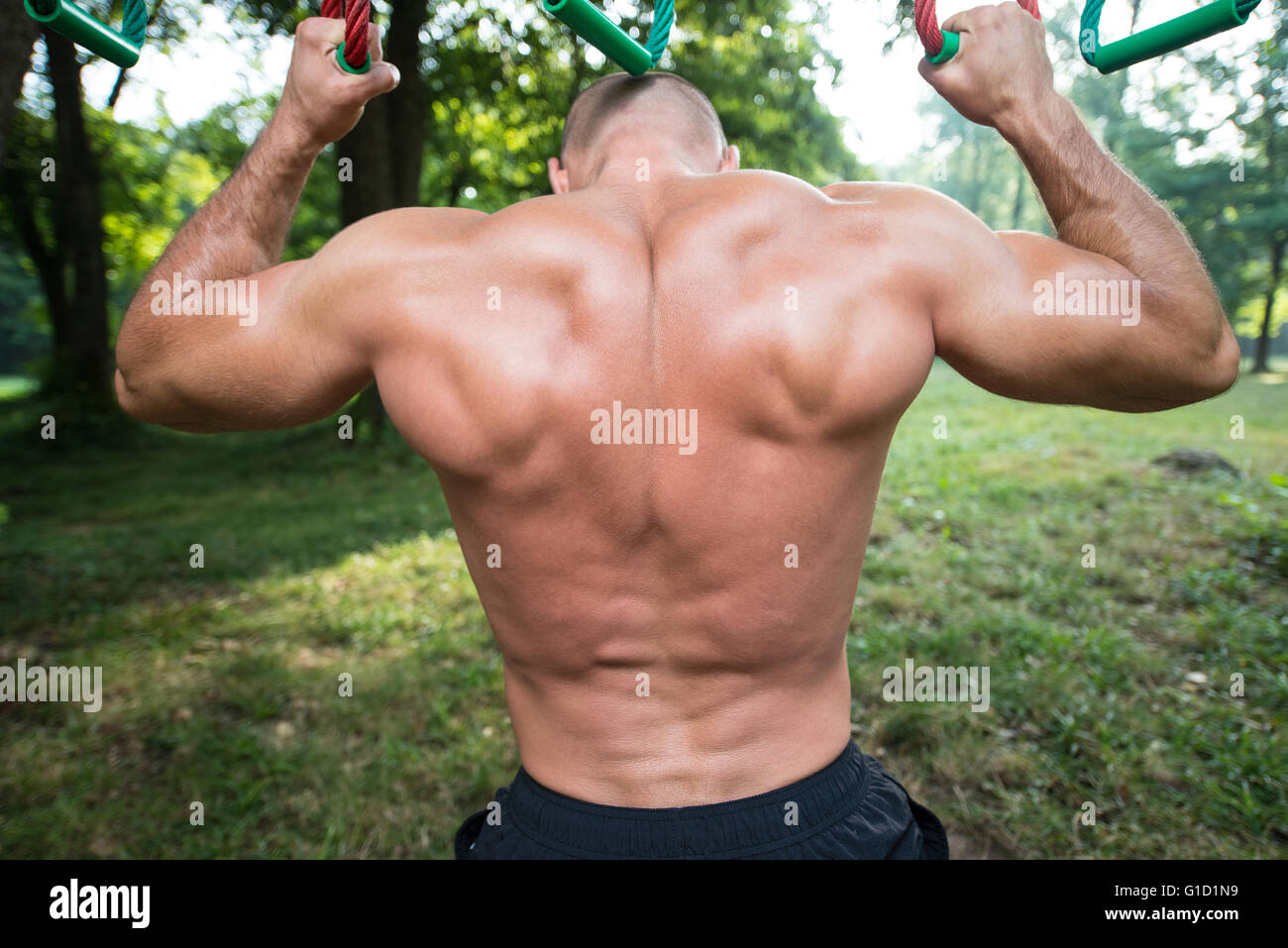 Close-Up Muscular Built Young Athlete Working Out In An Outdoor Gym - Doing Chin-Ups Stock Photo