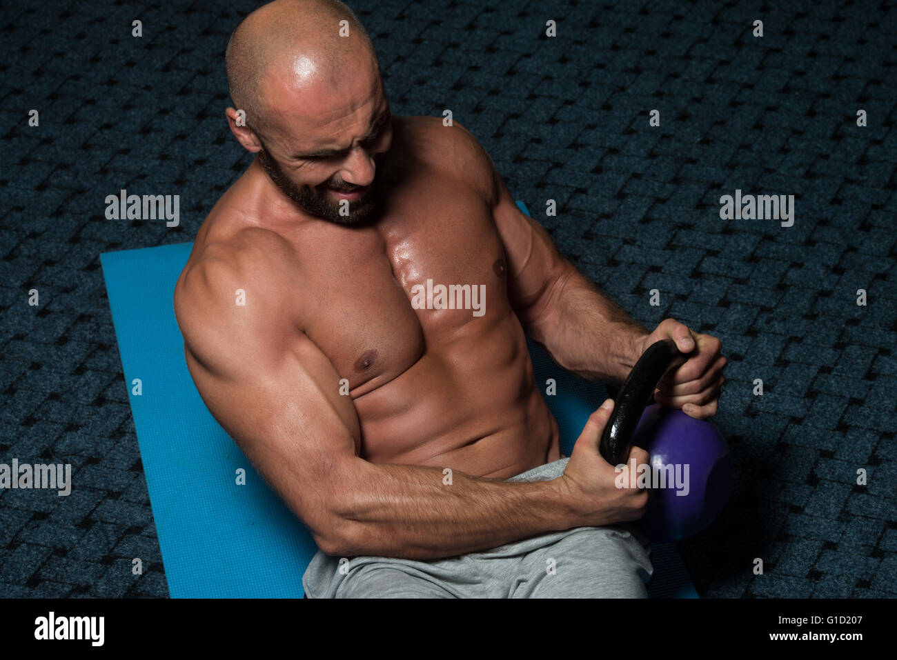 Muscular shirtless man workout with kettlebells in L Sit position outdoors.  Stock Photo