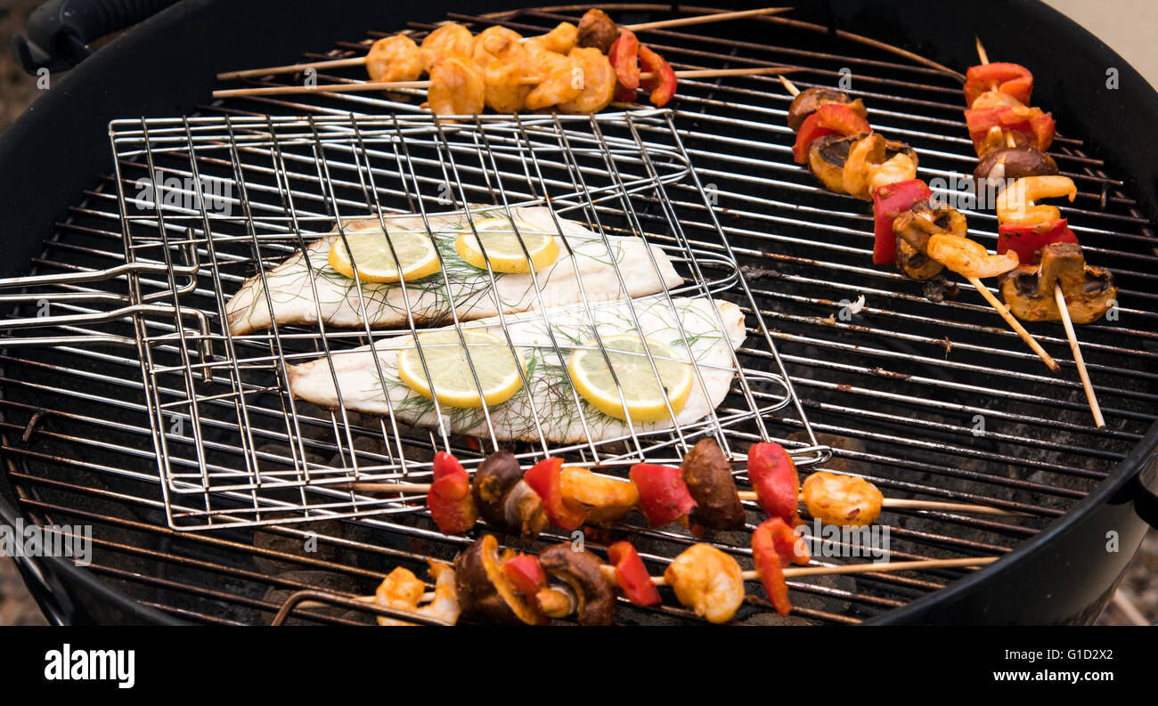 Summer BBQ.  Fish and vegetables being cooked on a grill outdoors Stock Photo