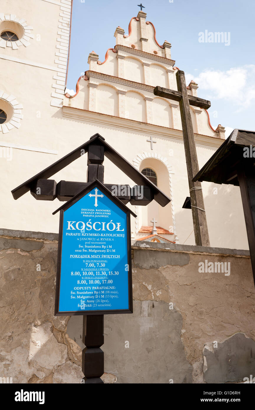 Informational church cross in Janowiec village, Poland, Europe, blue board with mass schedule information in front of building. Stock Photo