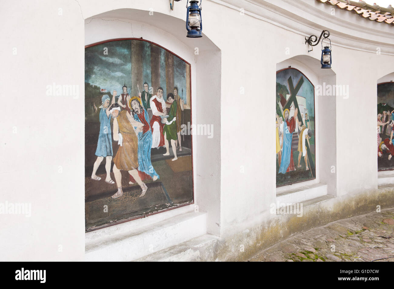 Stations of the cross wall paintings in niches of the churchyard concrete wall fencing in