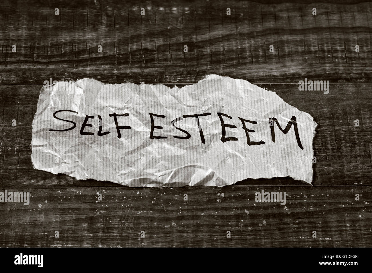 the text self esteem written in a piece of paper, placed on a rustic wooden surface, in black and white Stock Photo