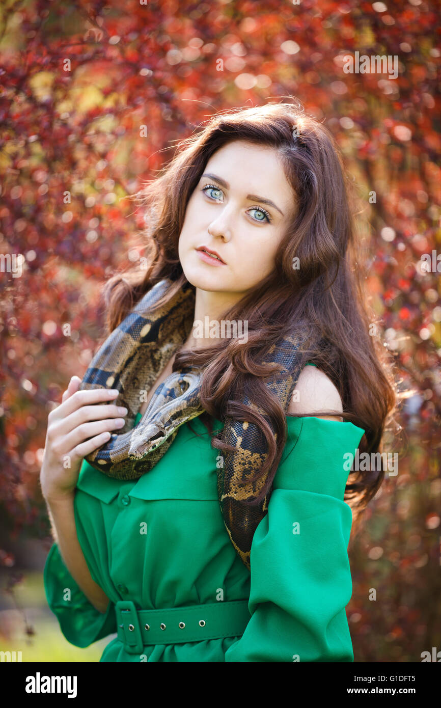 Portrait of the attractive teenage girl with snake in a garden Stock Photo