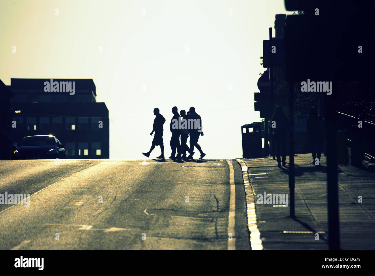 Silhouette of a group of 4 men on Glasgow street with road  contre- jour back-lit in  Glasgow,Scotland, UK. Stock Photo