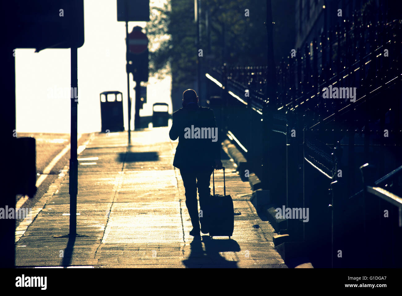 Silhouette of man on mobile phone on Glasgow street with road contre- jour backlit in  Glasgow,Scotland, UK. Stock Photo