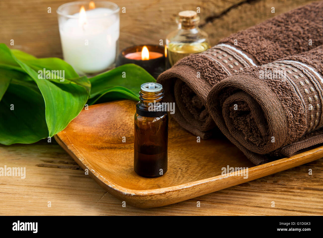 Spa treatment oil, candles and cotton towels Stock Photo