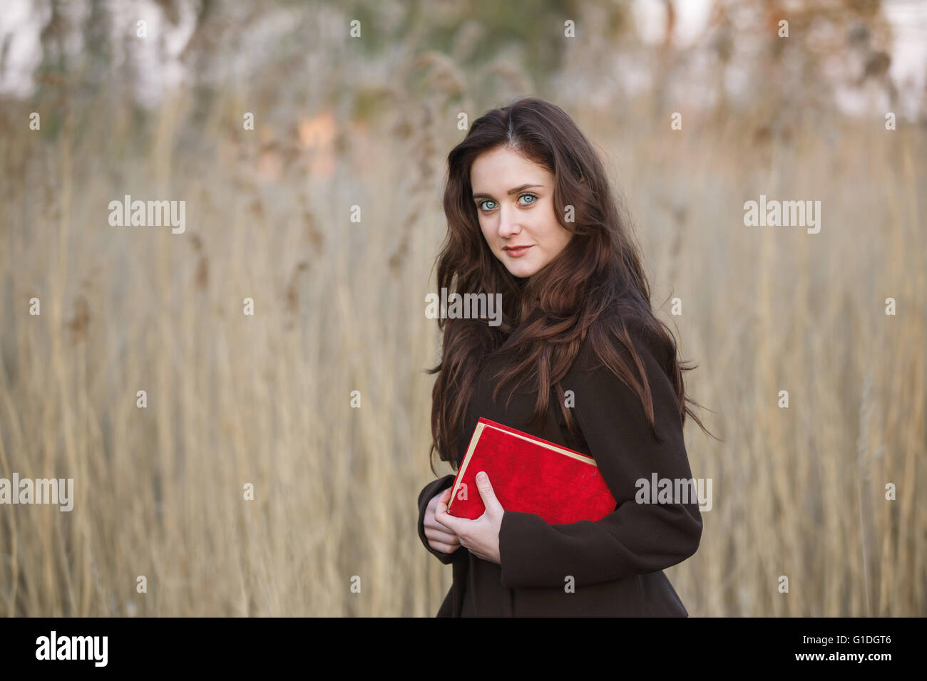 Portrait of attractive teenage girl with red book Stock Photo - Alamy