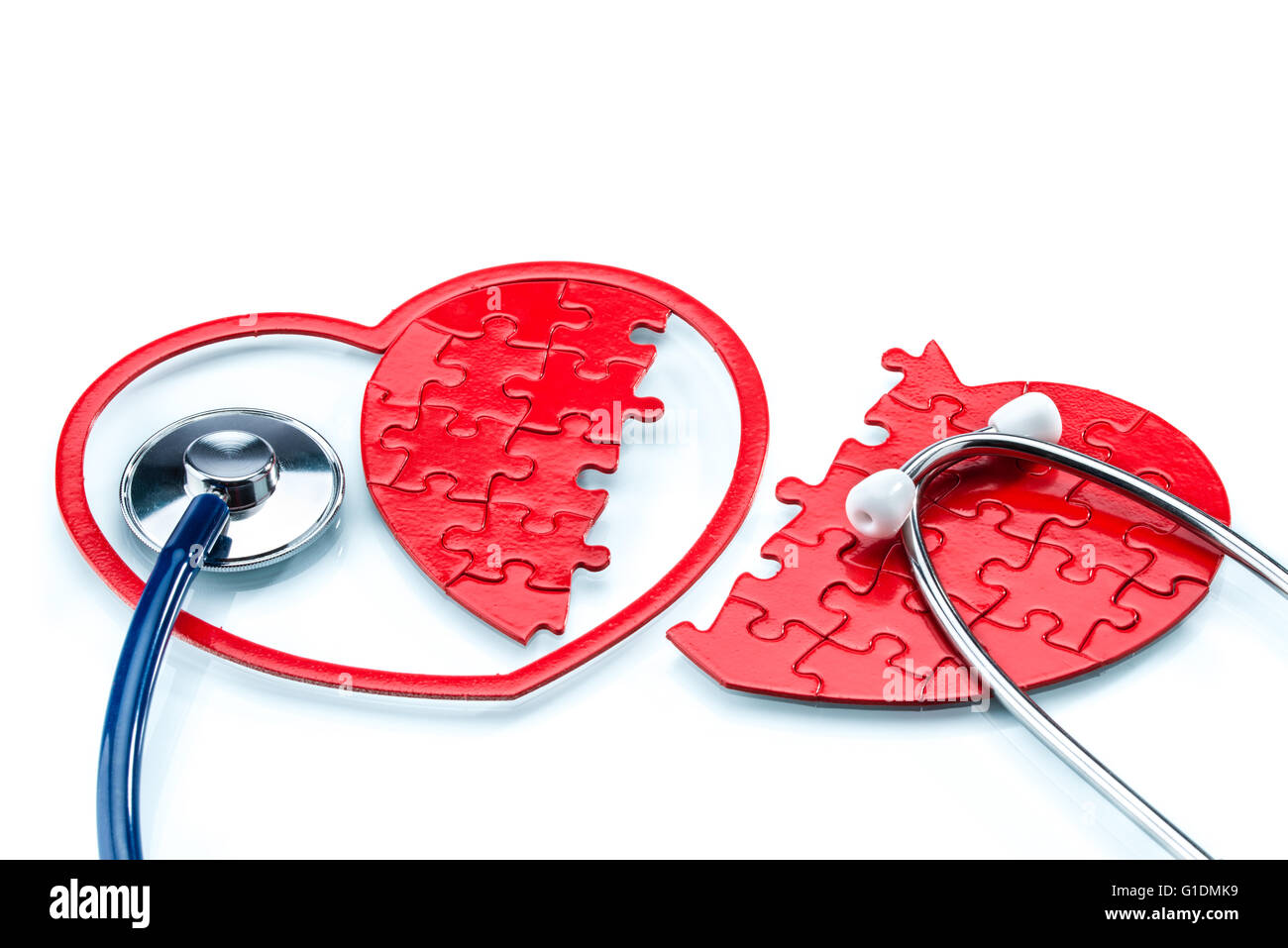 Heart disease, Split heart-shaped puzzle with stethoscope on white background Stock Photo