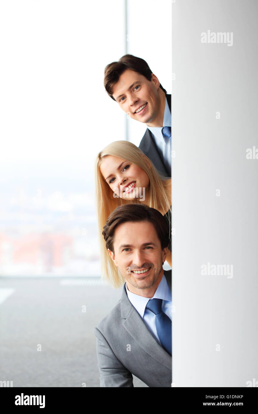 Happy business people looking out from corner in office Stock Photo - Alamy