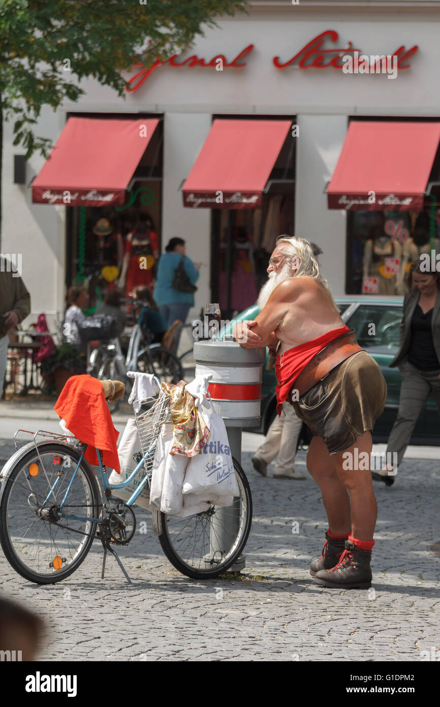 Funny old man summary dressed in leather pants, drink a glass of beer in Munich Stock Photo